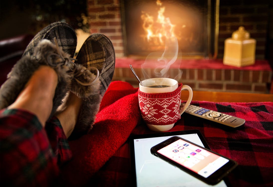 Lots of technology on a table in front of a warm fire