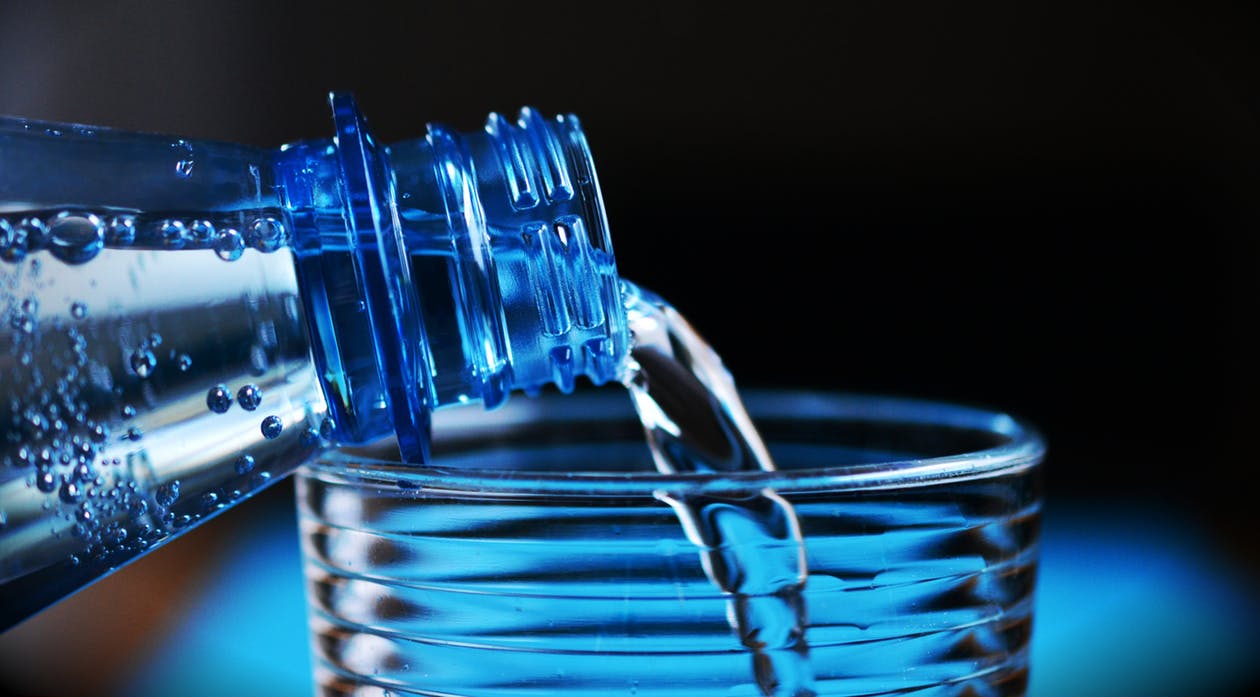 Pouring bottle of water into glass